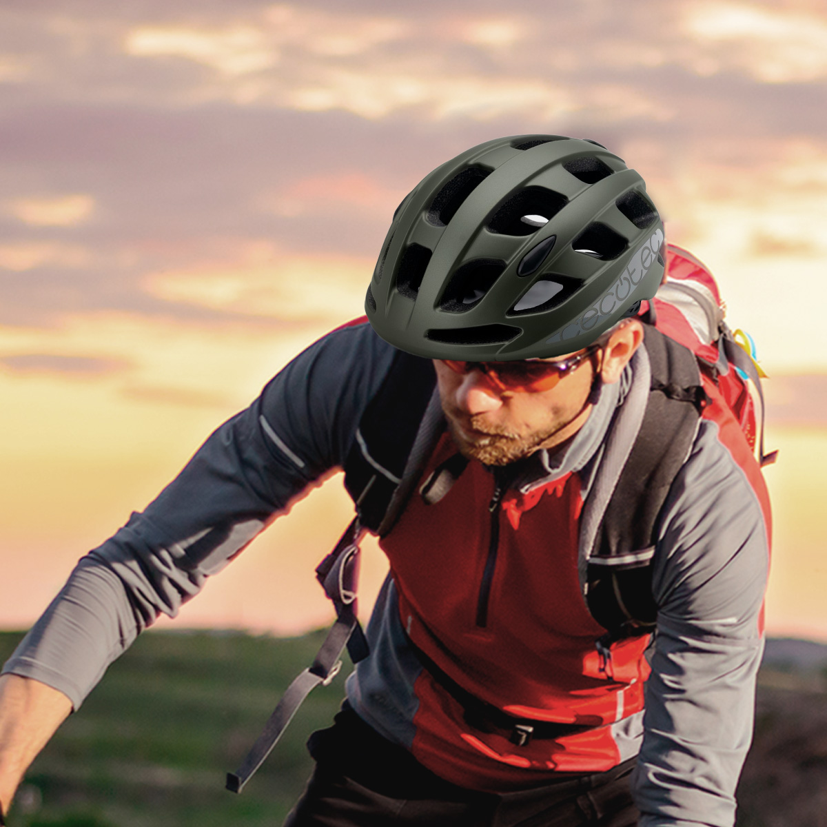 Ciclista con casco verde y gafas de sol, con mochila. El fondo muestra una puesta de sol.