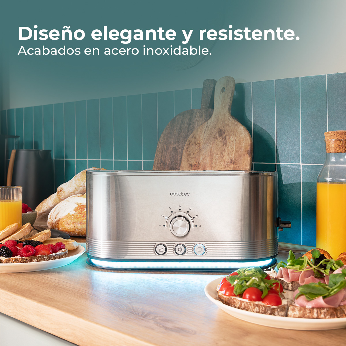 Una tostadora de acero inoxidable con pan, sándwiches y jugo en una encimera de madera. Dos tablas de cortar en el fondo.