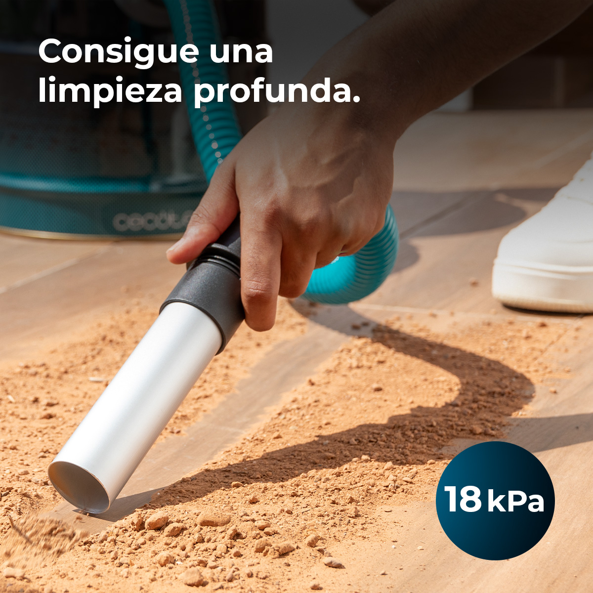 Una mano tiene un ugello di un aspirapolvere che pulisce lo sporco. L'immagine ha testo in spagnolo. Un cerchio blu mostra '18 kPa'.