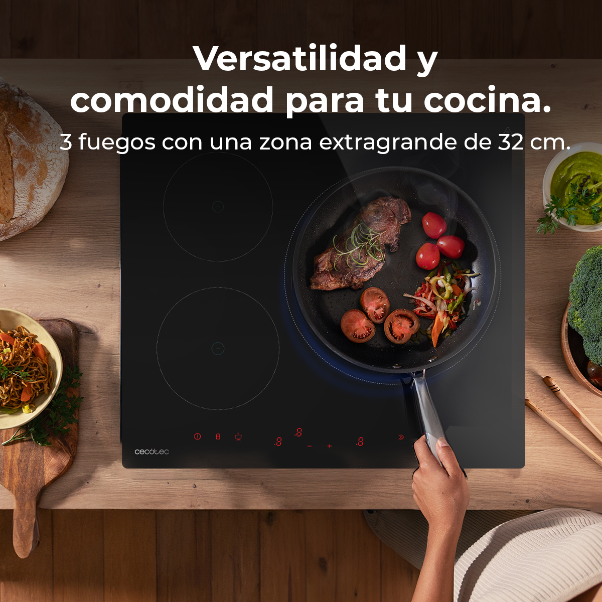 Czarna płyta indukcyjna z patelnią smażącą stek i warzywa. Widoczne inne produkty spożywcze i tekst w języku hiszpańskim.