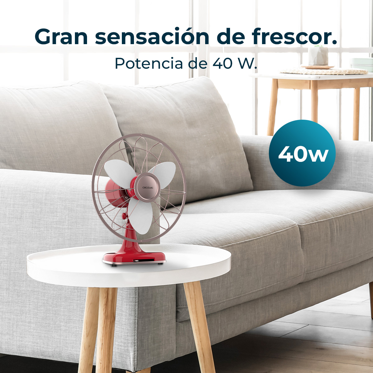 Un ventilador rojo y blanco está sobre una mesa blanca frente a un sofá gris. Un círculo azul con '40W' está a la derecha.