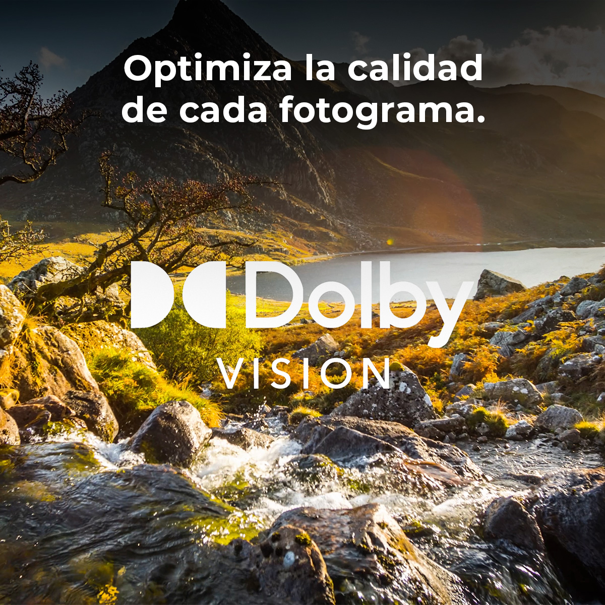 Krajobraz górski z jeziorem, strumień na pierwszym planie. Logo Dolby Vision i tekst po hiszpańsku. Światło słoneczne.