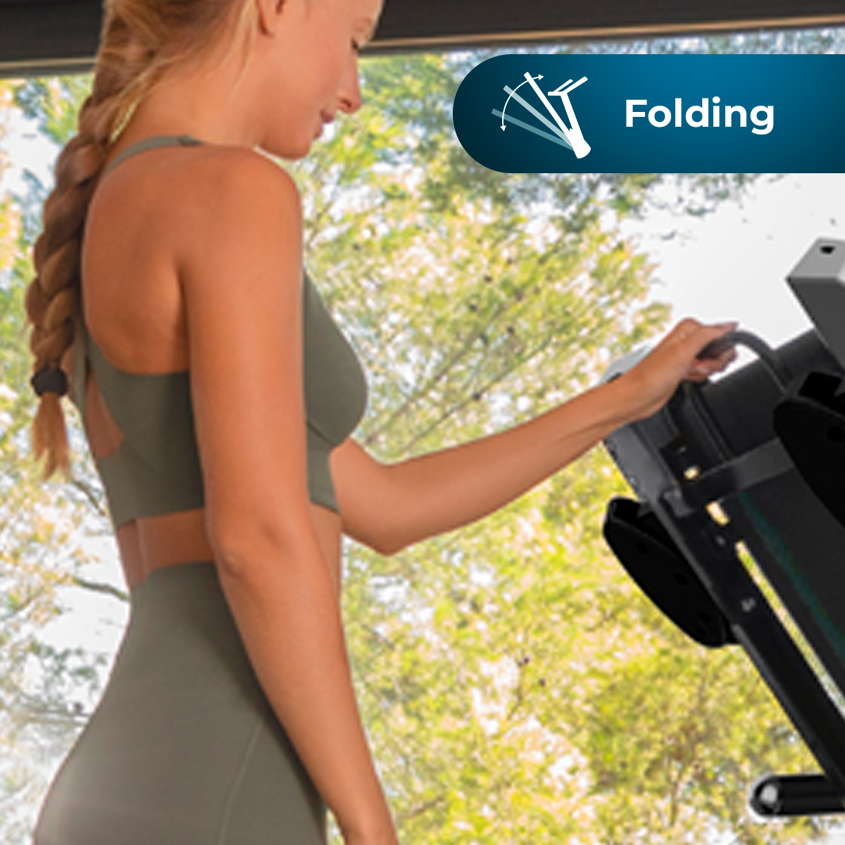 Kobieta w oliwkowym stroju sportowym składa bieżnię. Zielone liście za oknem. Tekst mówi 'Składany'.