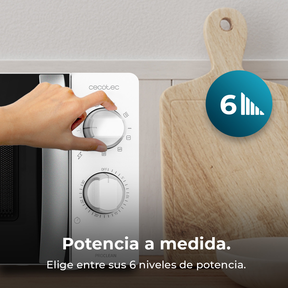 Una mano gira el dial del microondas. El microondas es blanco, con una tabla de cortar de madera a la derecha y un icono azul de nivel de potencia.