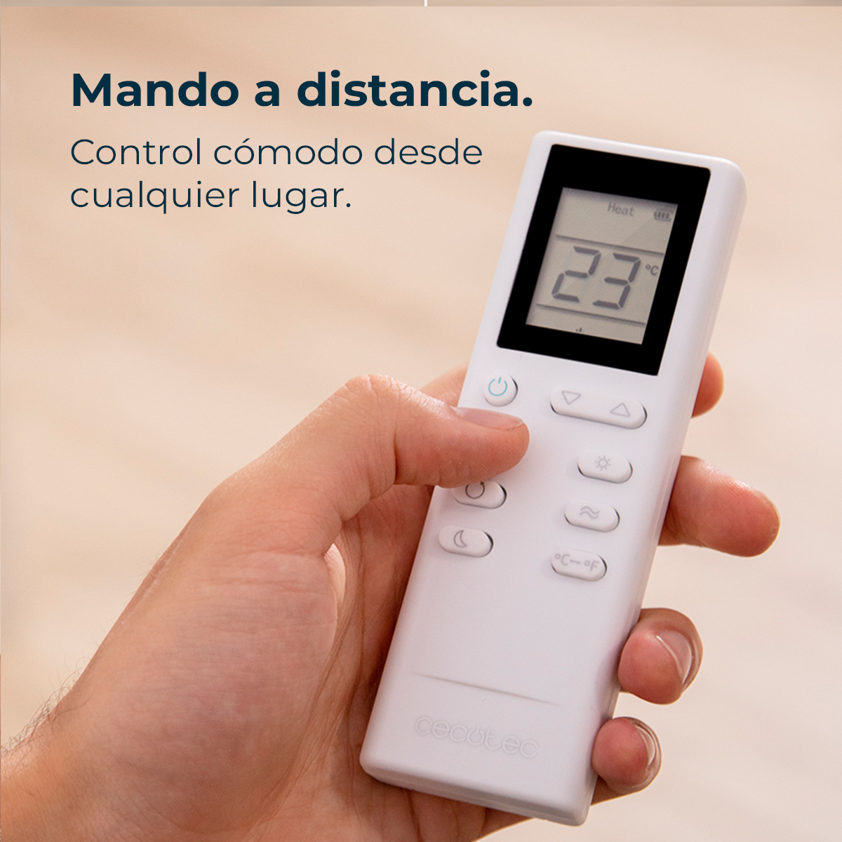 Dłoń trzyma biały pilot z wyświetlaczem 23°C. Pilot ma kilka przycisków. Tło jest rozmyte.