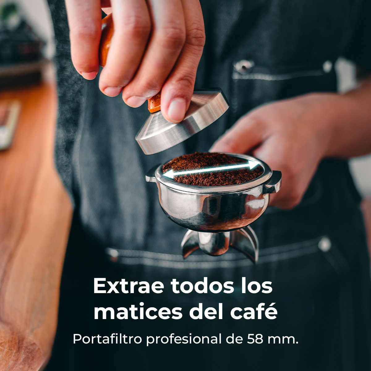 Un barista presiona granos de café en un portafiltro con un pisón. El portafiltro es plateado y los granos son marrones.