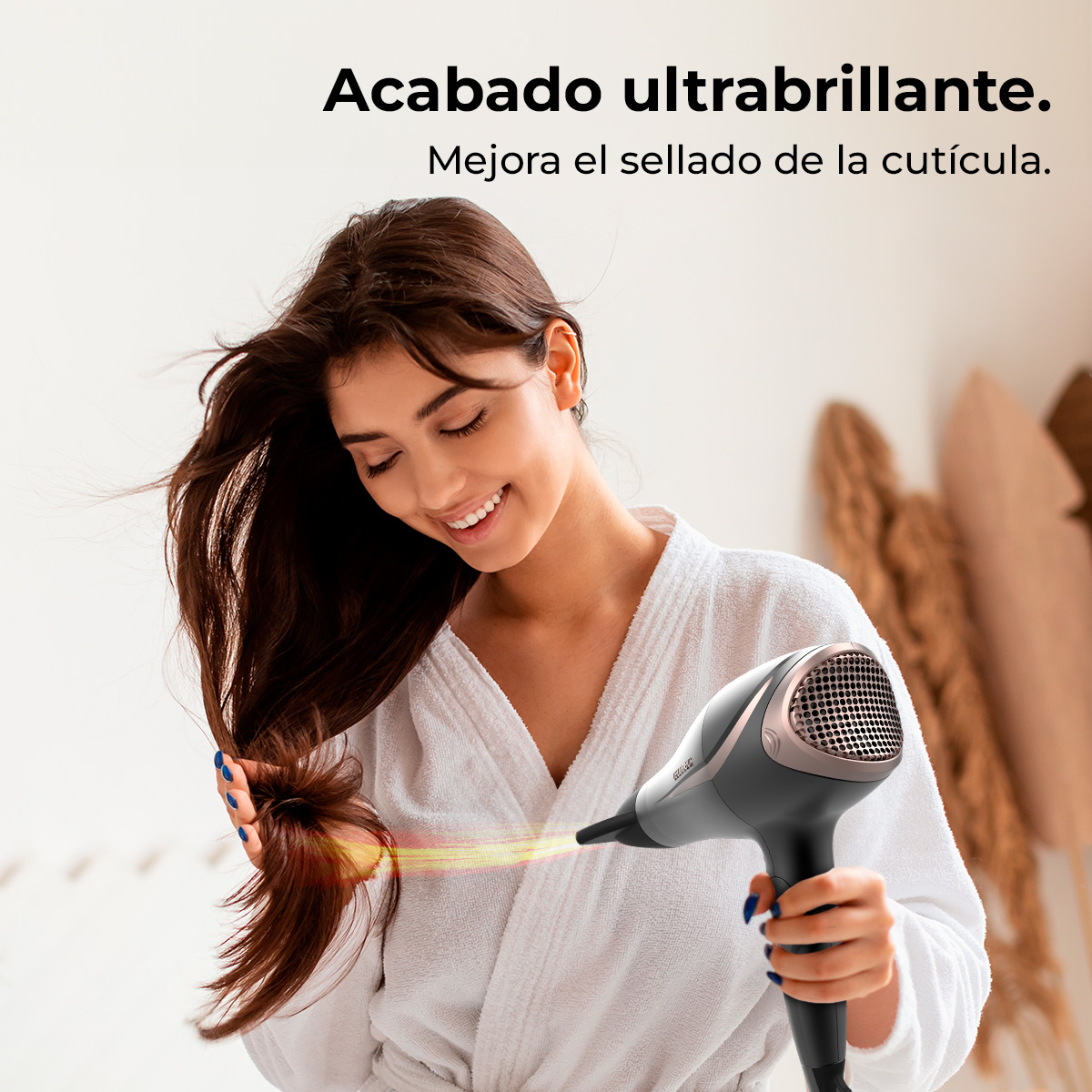 Una donna in accappatoio bianco sorride mentre si asciuga i capelli con un asciugacapelli. Testo in spagnolo in alto.