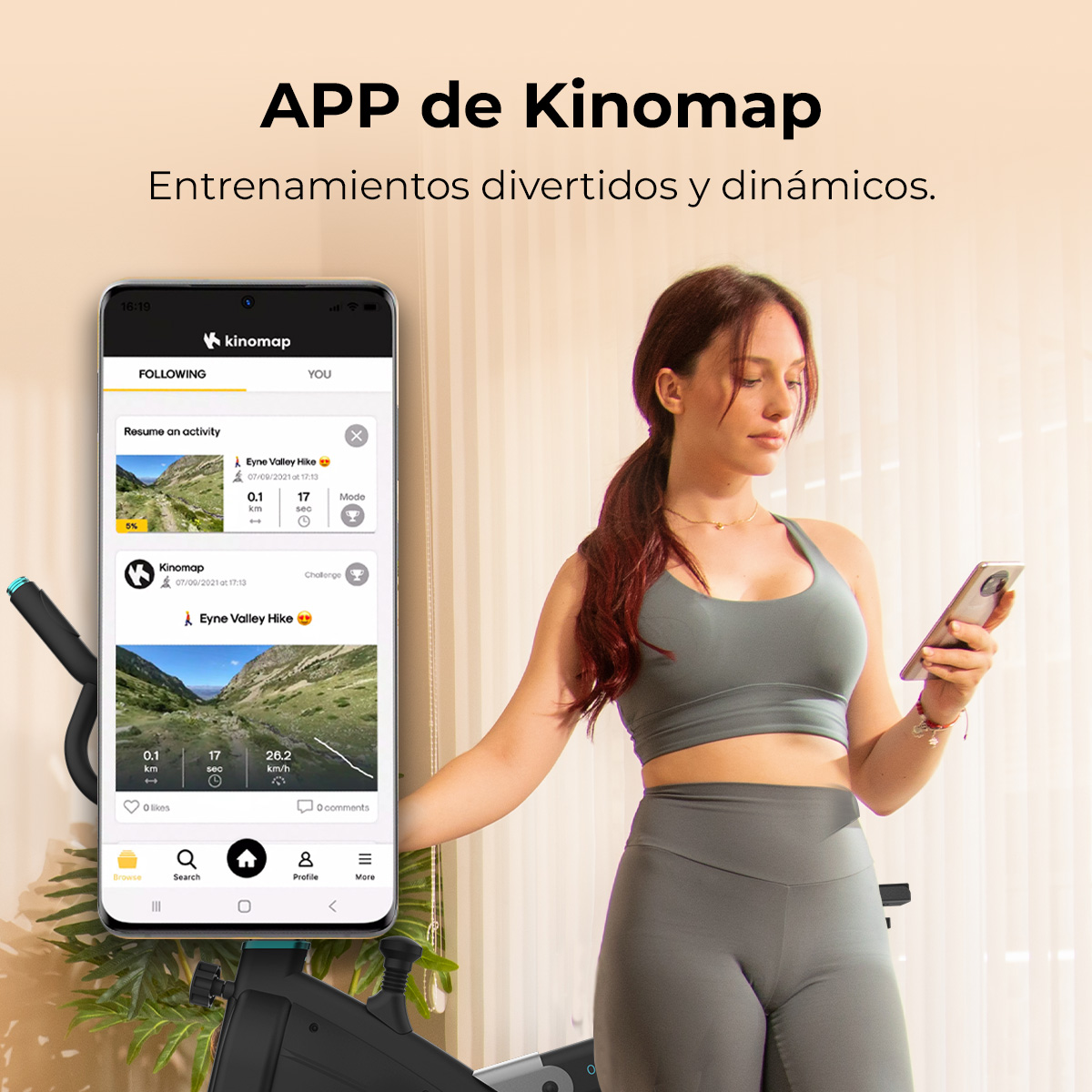 Una mujer con un teléfono, mirándolo. Un teléfono muestra la aplicación Kinomap. Una bicicleta estática está en primer plano.