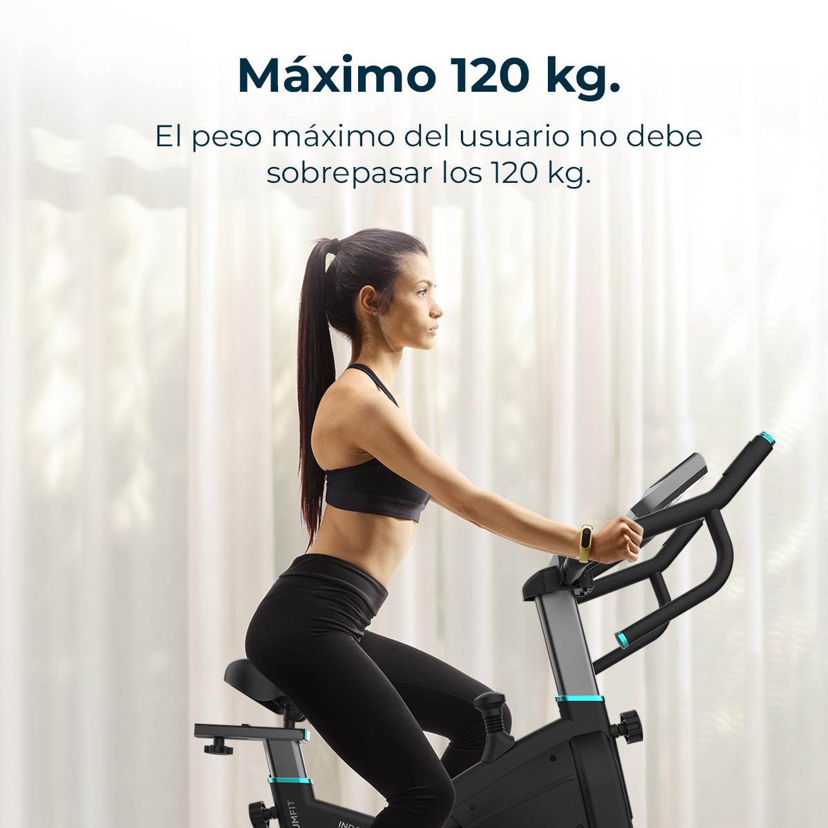 Una mujer se ejercita en una bicicleta estática. Lleva ropa deportiva negra. El texto superior dice 'Máximo 120 kg'.