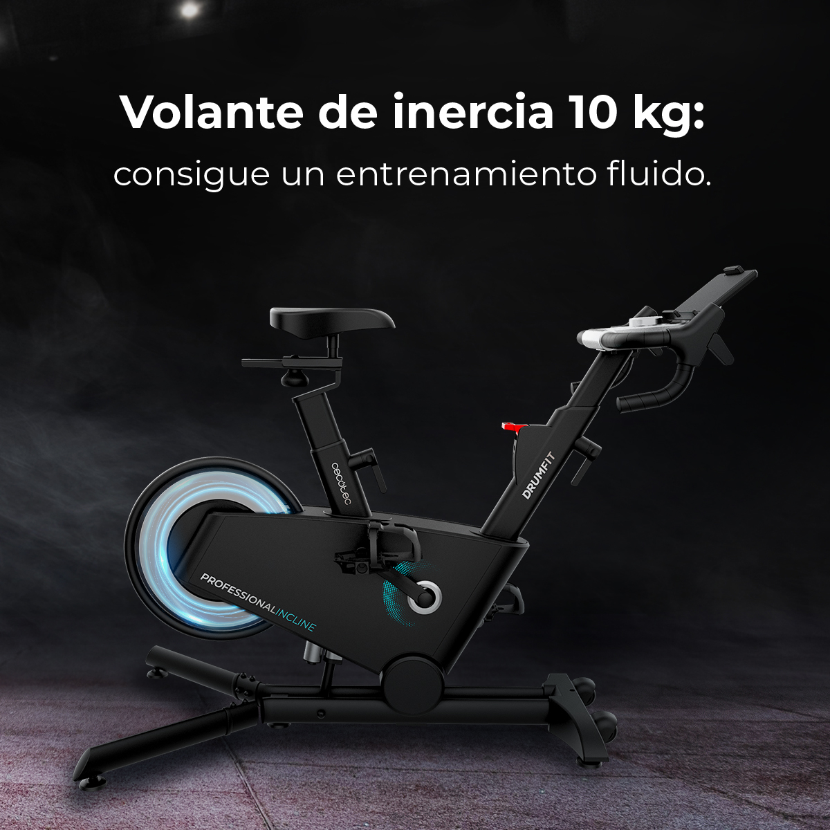 Czarny rower treningowy z kołem zamachowym i napisem 'Volante de inercia 10 kg' na ciemnym tle.