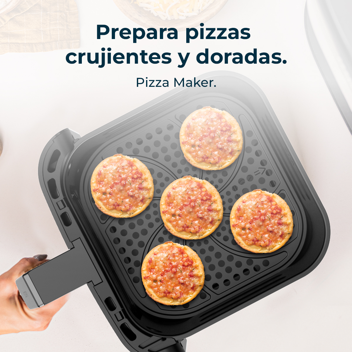 Pięć mini pizz w czarnej maszynie do pizzy. Pizze są złociste z czerwonymi dodatkami, na białej powierzchni.