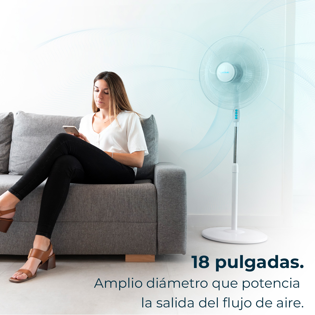 Kobieta na szarej sofie używa telefonu, obok białego wentylatora. Tekst: 18 cali i opisuje przepływ powietrza.