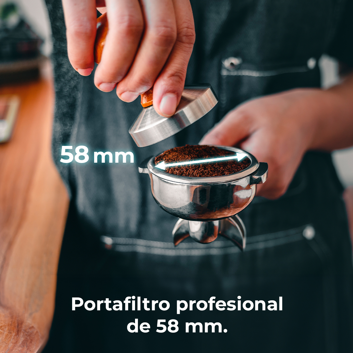 Eine Person presst Kaffeepulver in einem Siebträger mit einem Tamper. Das Bild enthält Text: 58 mm und Portafilter profesional de 58 mm.