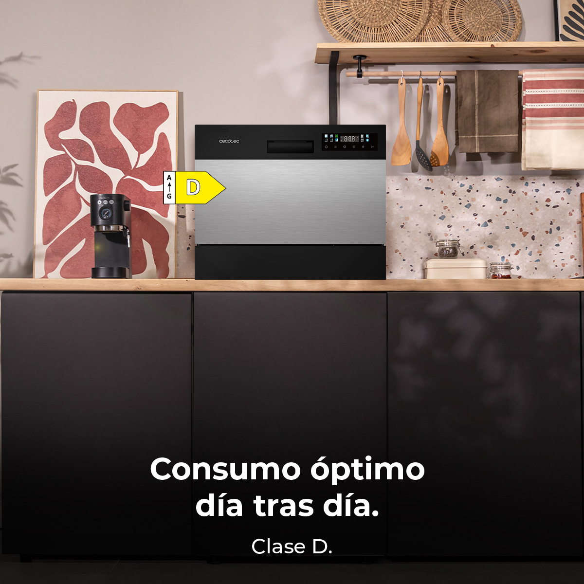 Scena di cucina con lavastoviglie. Macchina del caffè e opera d'arte su un bancone di legno. Testo: 'Consumo ottimale giorno dopo giorno. Classe D.'