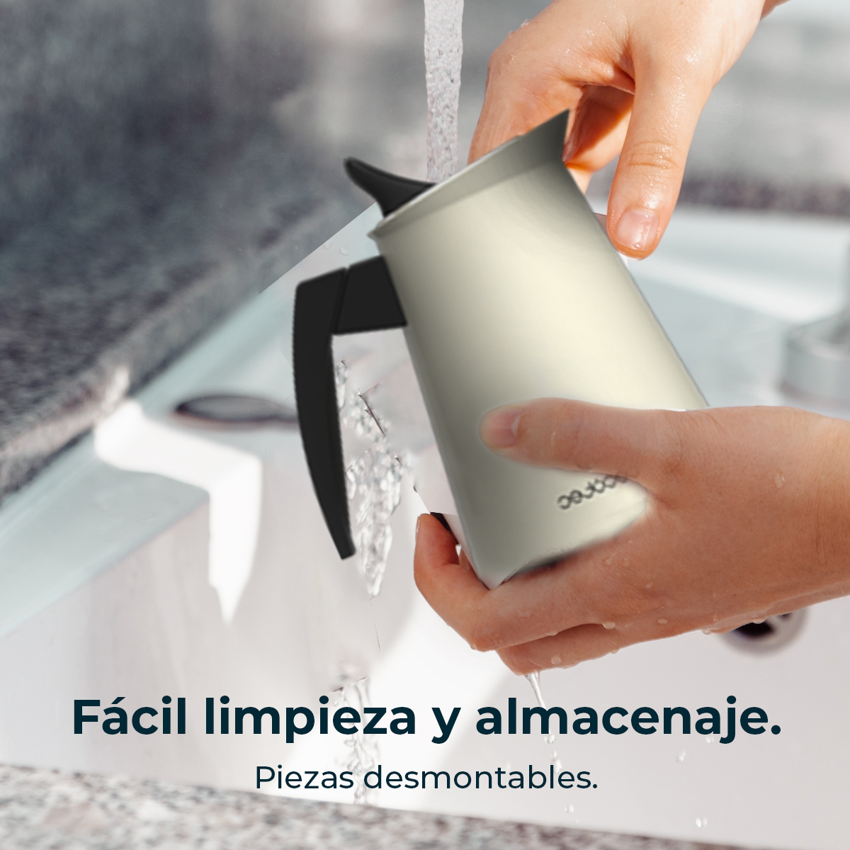 Una persona lava una brocca color crema con manico nero sotto l'acqua corrente in un lavandino.