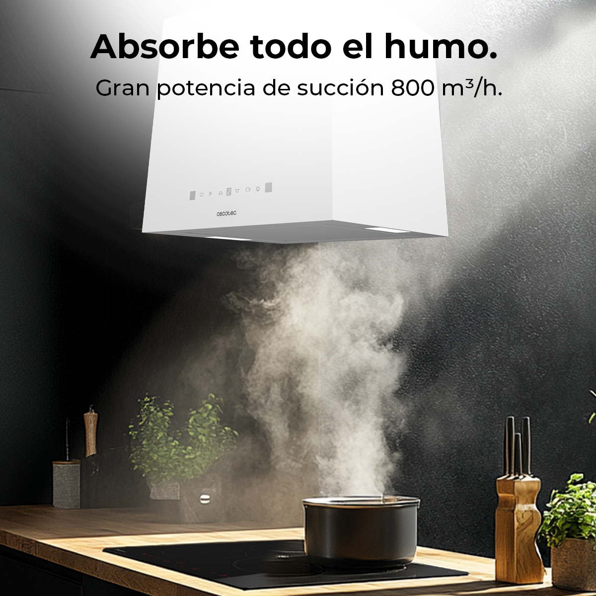 Una campana extractora blanca sobre una olla en una estufa, extrayendo vapor. El fondo es una pared oscura con una encimera de madera y plantas.