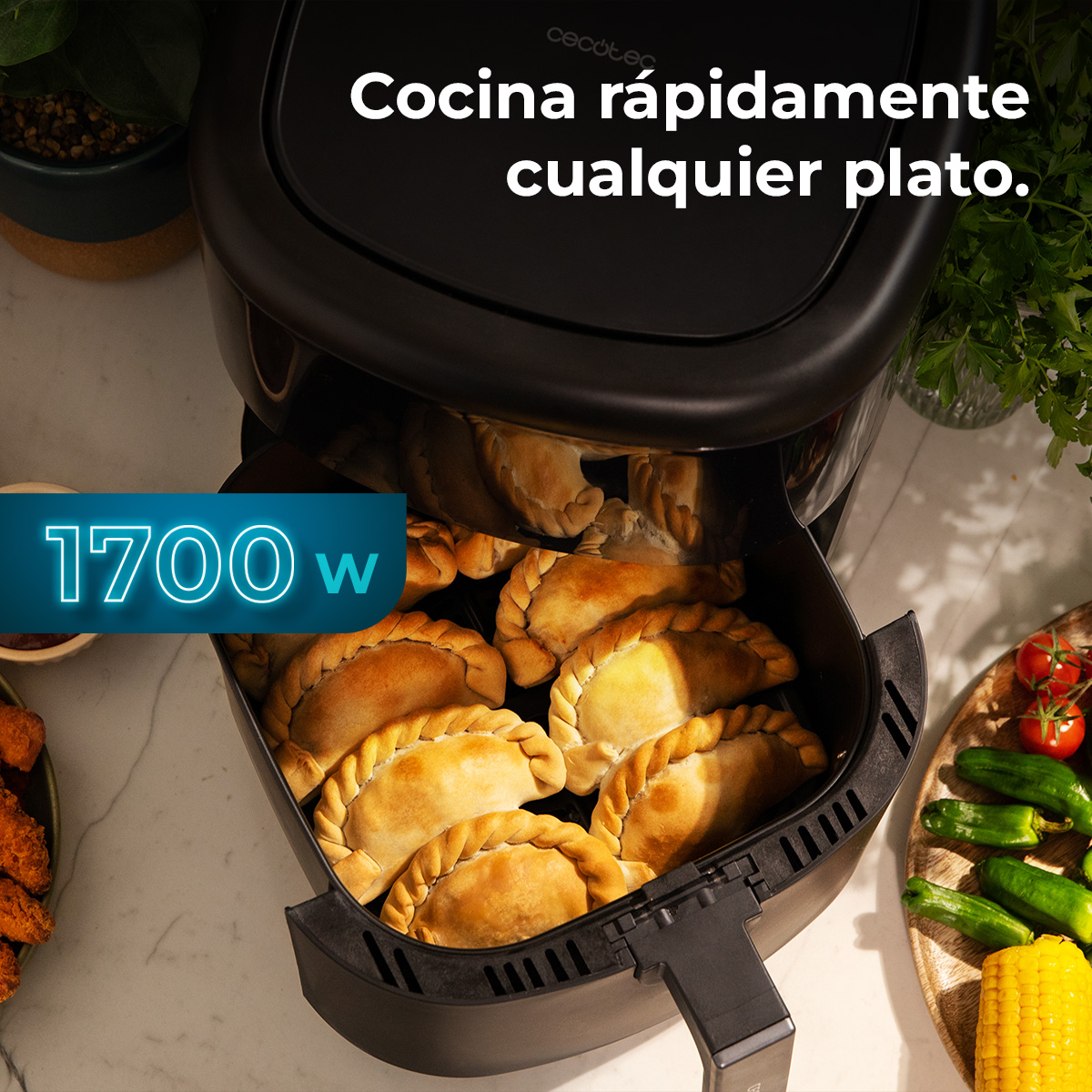 Een airfryer met empanadas erin. Tekst bovenaan: Kook snel elk gerecht. Vermogen 1700 W. Groenten aan de zijkant.