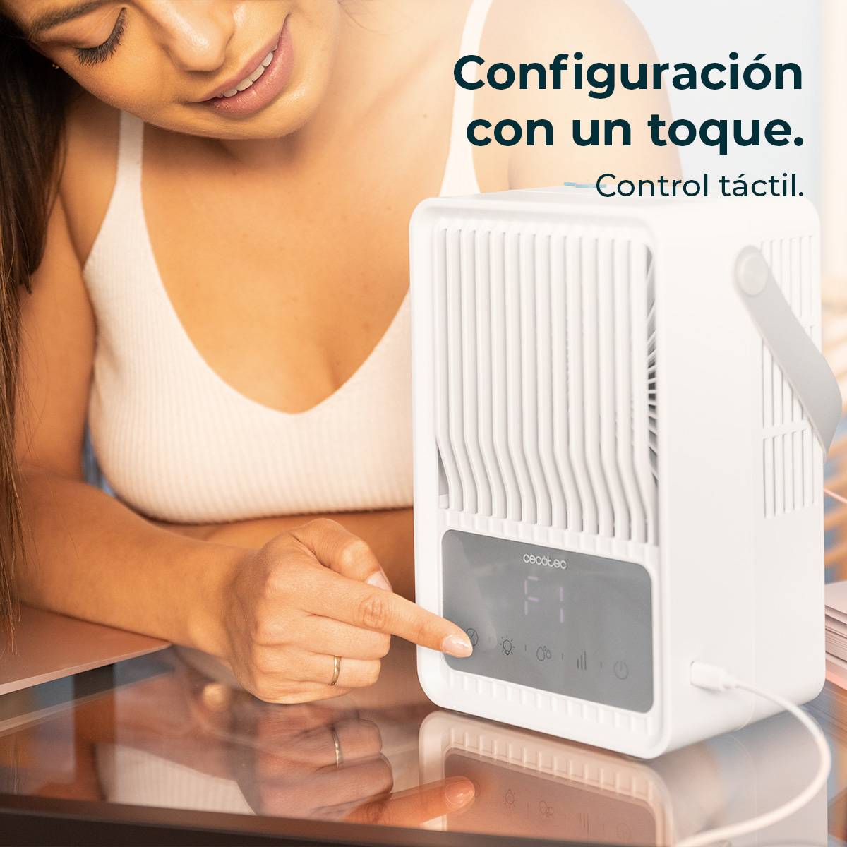 Una donna indica un ventilatore bianco con display digitale. Il ventilatore è su una superficie riflettente.