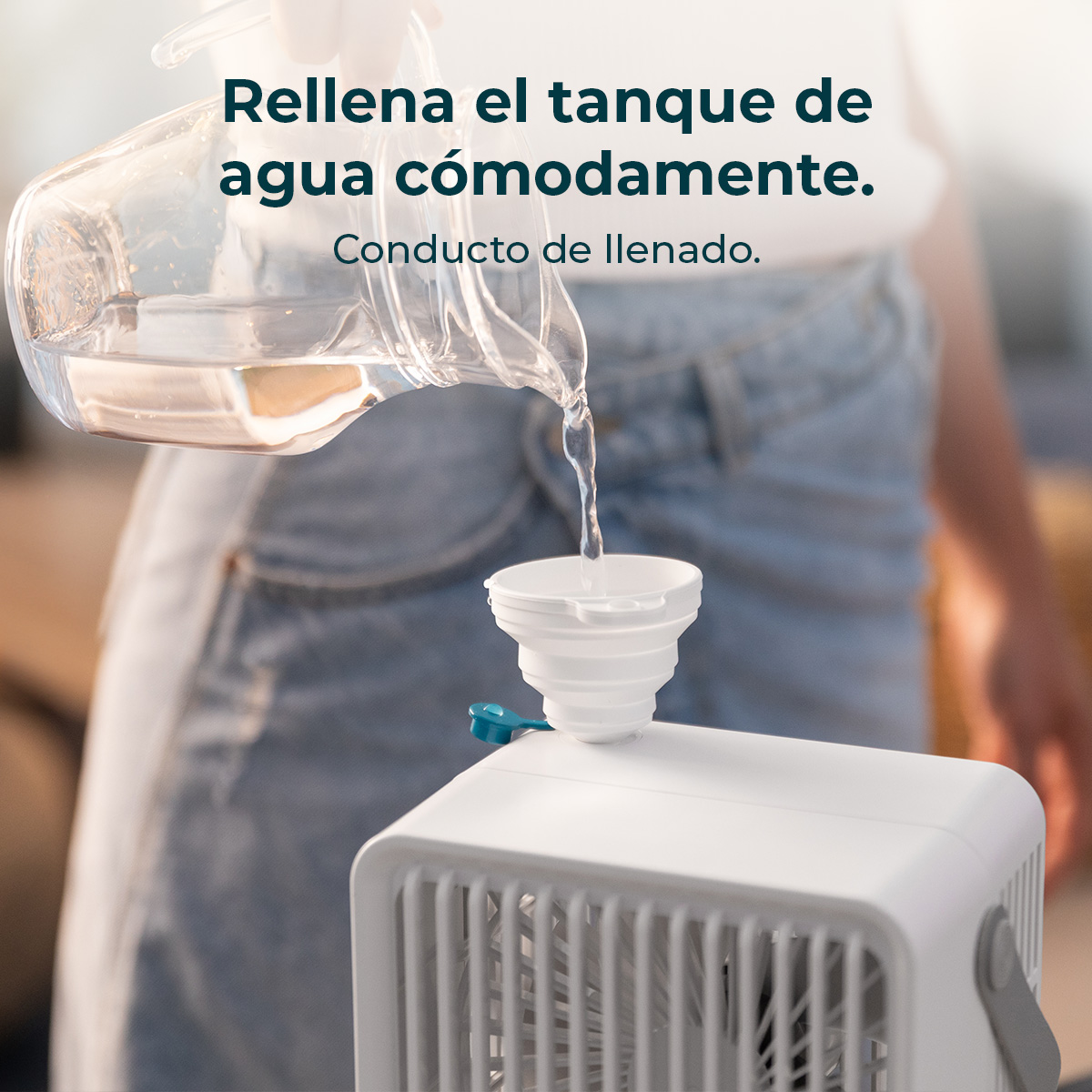 Una persona versa acqua da una brocca in un imbuto bianco, posto su un ventilatore bianco.