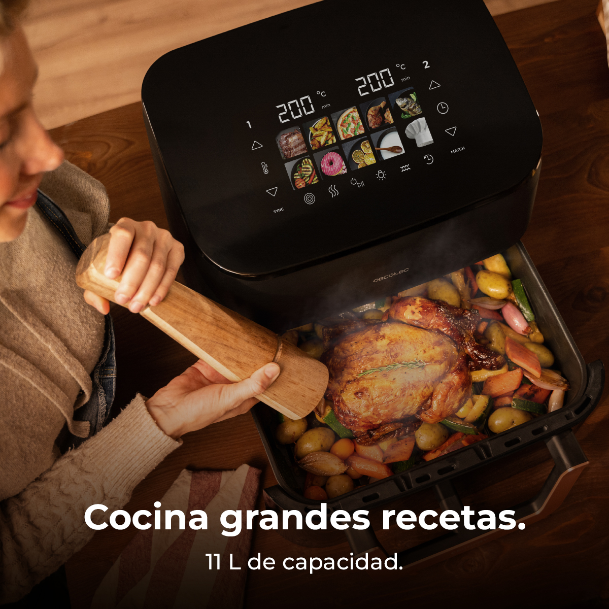 Una donna usa una friggitrice ad aria. Un pollo arrosto è nel vassoio con verdure. La friggitrice ha un display digitale.