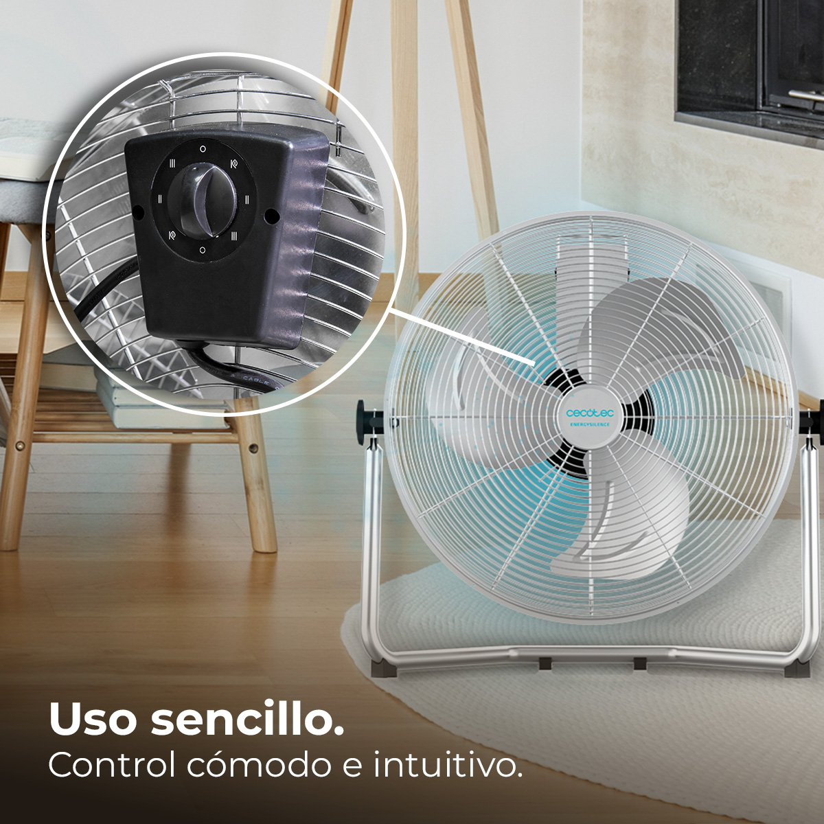 Srebrny wentylator podłogowy z czarnym panelem sterowania. Wentylator stoi na białym dywanie, w tle drewniane meble.