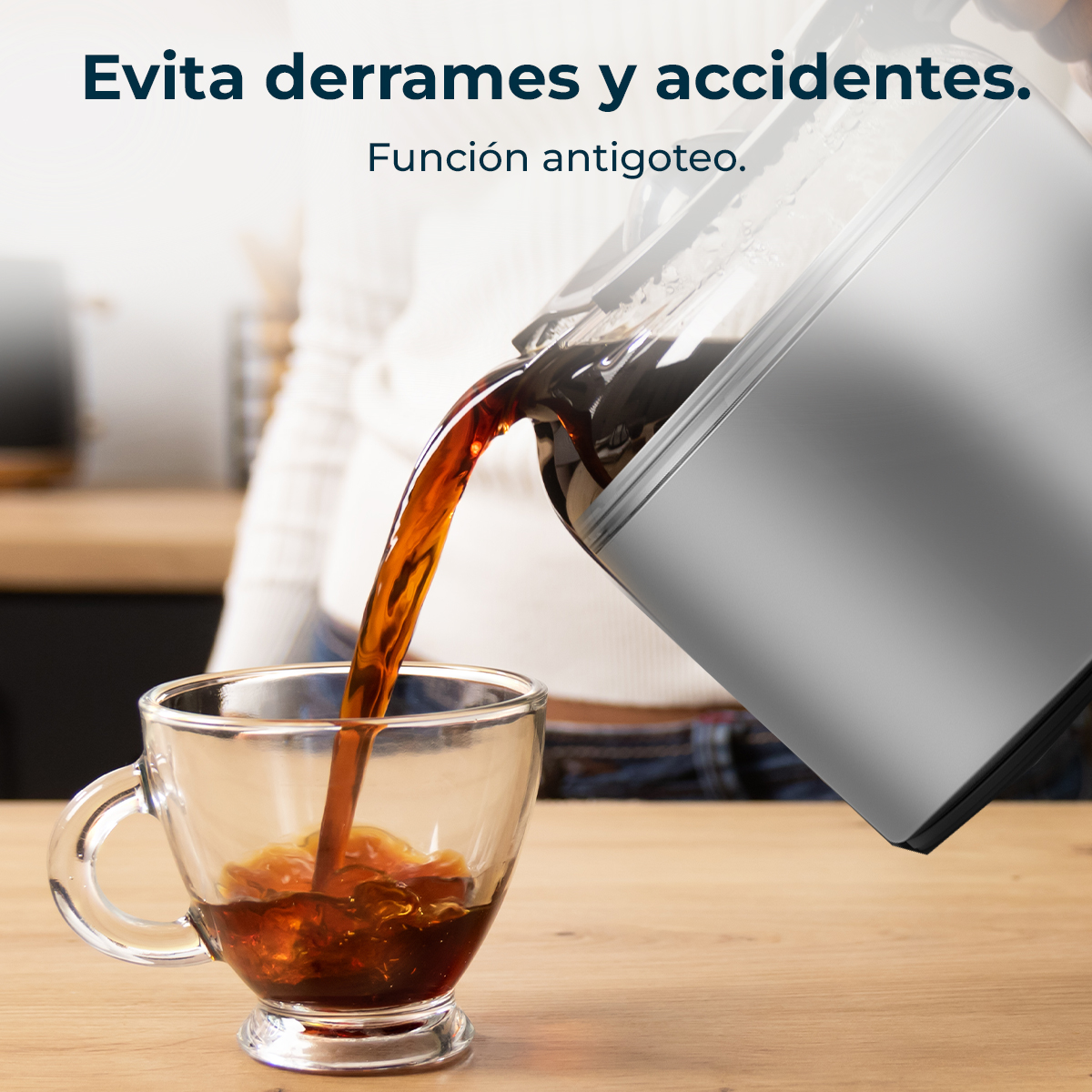 Kawa jest wlewana ze srebrnego ekspresu do kawy do przezroczystego szklanego kubka. Kubek stoi na drewnianym stole.