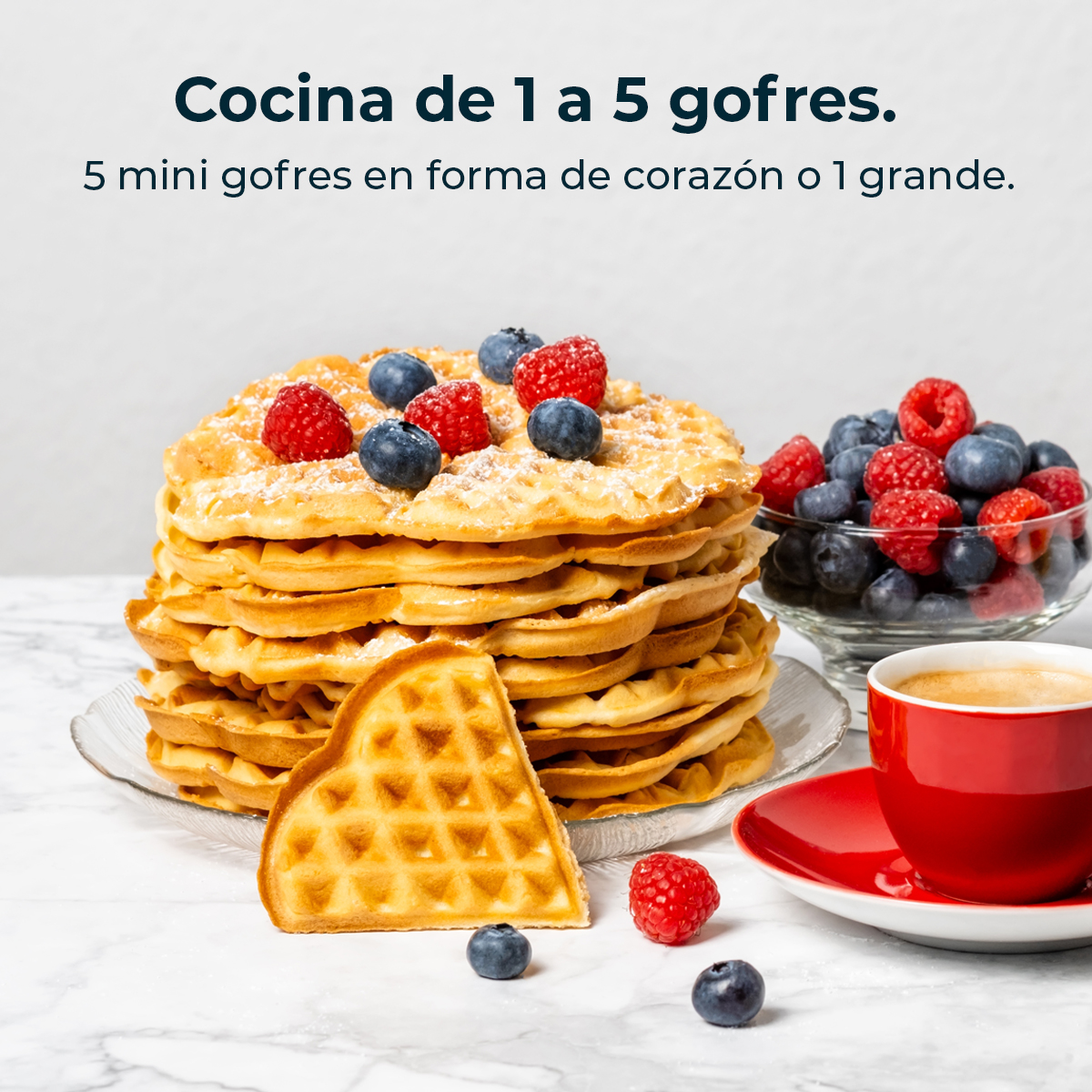 Una pila di waffle con frutti di bosco e zucchero a velo. Un waffle a forma di cuore è davanti, con una tazza di caffè.