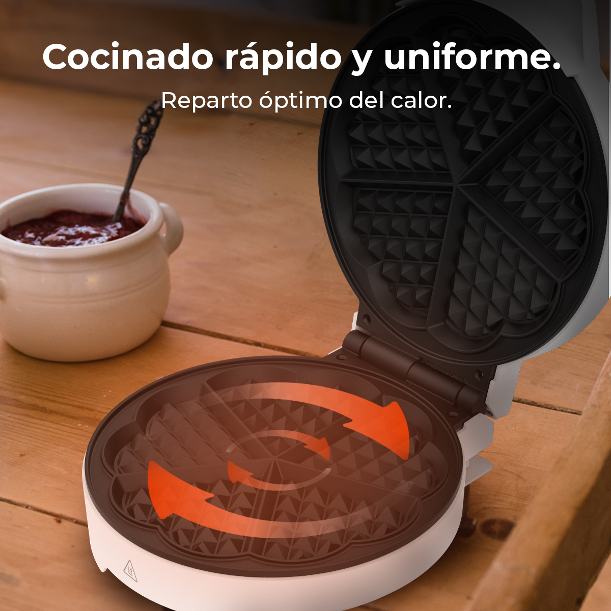 Waffle maker aperto, che mostra la superficie di cottura. Frecce indicano la distribuzione del calore. Vasetto di marmellata e cucchiaio.