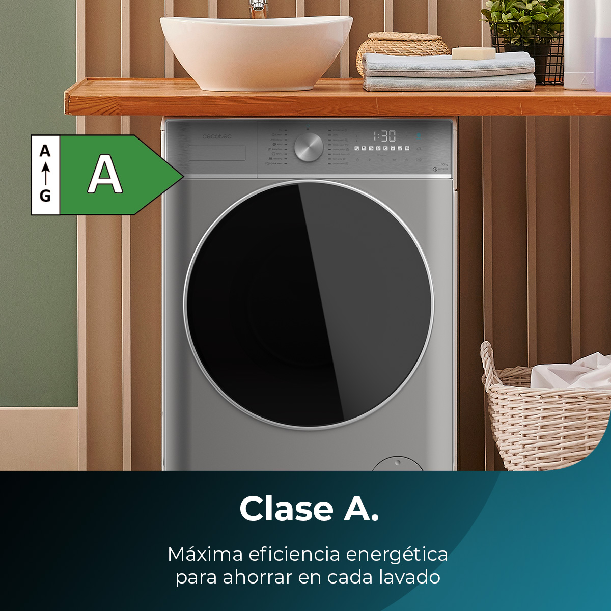 Szara pralka z czarnymi drzwiami, etykieta efektywności energetycznej 'A' i tekst 'Clase A'. Tło łazienki z umywalką i koszem.