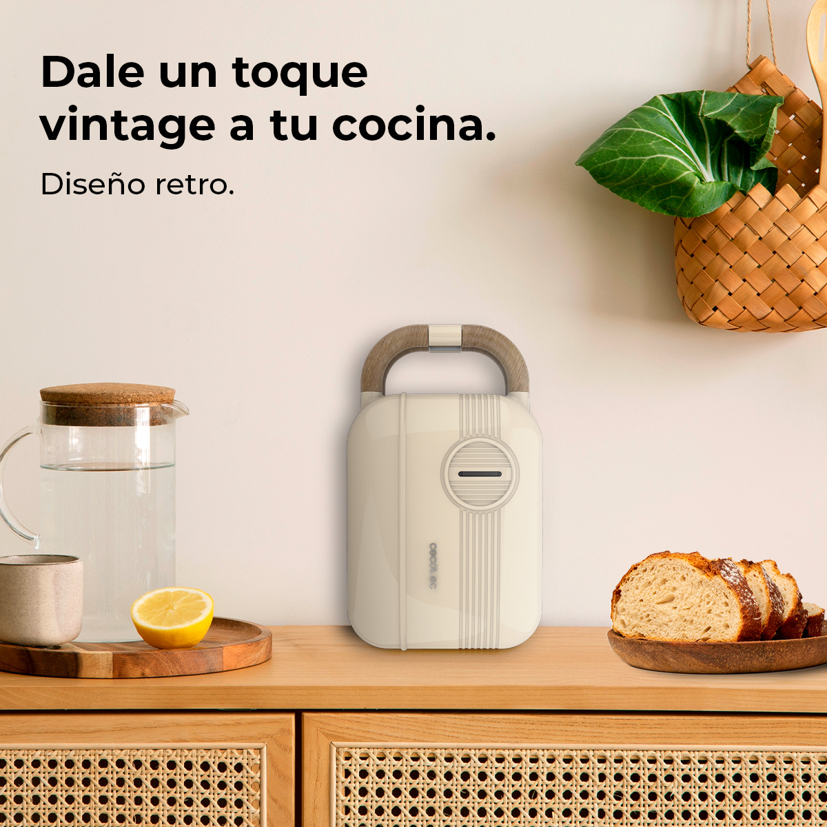 Un elettrodomestico color crema con manico in legno è appoggiato su un ripiano in legno. Sono presenti una pagnotta, una caraffa di vetro e un limone.
