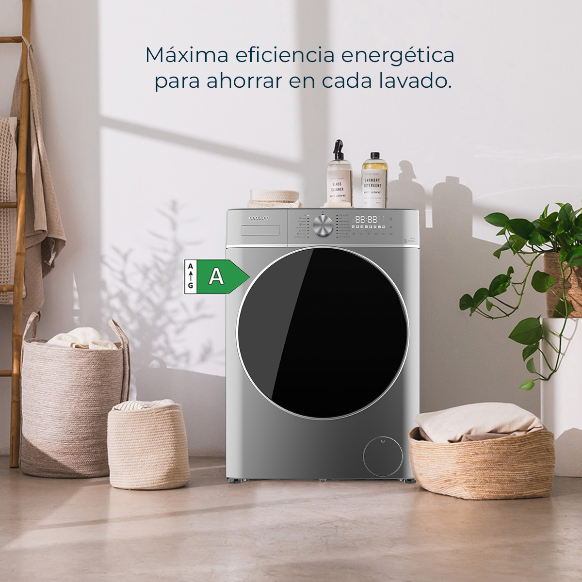 Lavatrice grigia con etichetta energetica 'A'. Cesti per la biancheria, piante e prodotti per la pulizia nella scena.