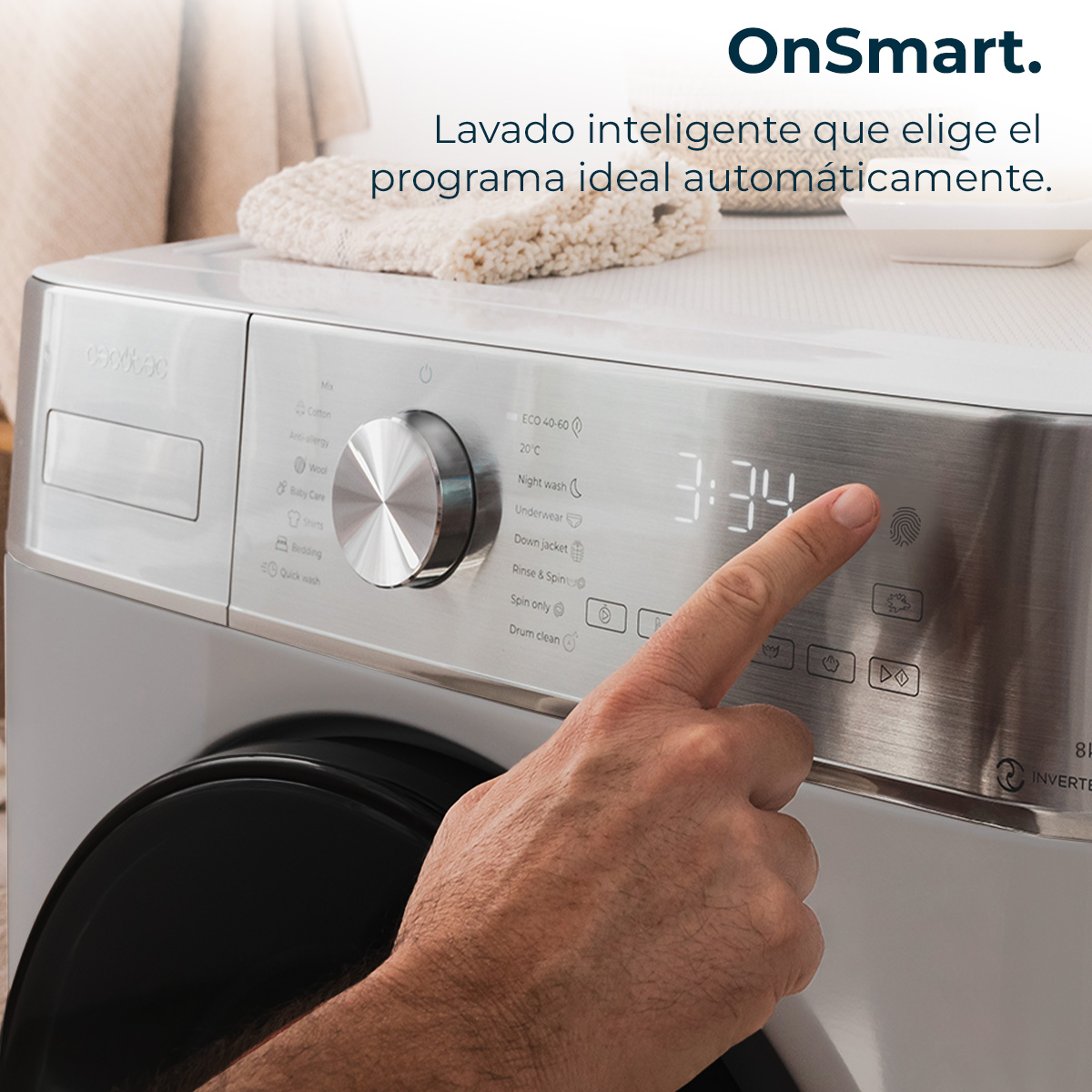 Una mano tocca il pannello di controllo di una lavatrice. Il display mostra 3:34. La macchina è bianca con il marchio OnSmart.