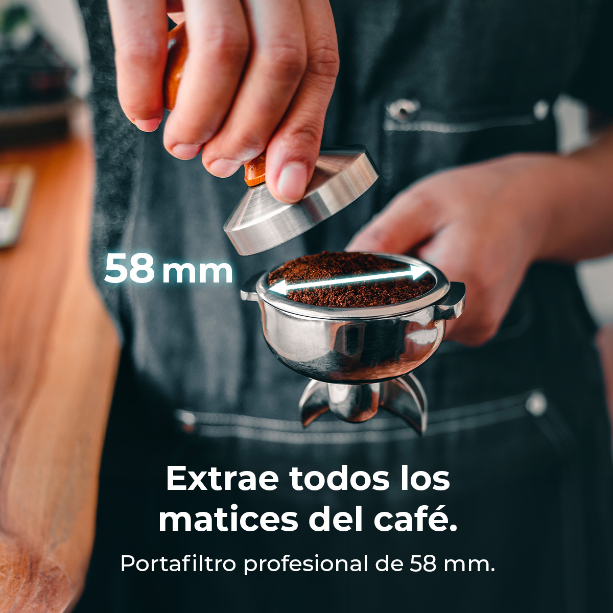 Osoba wciska zmieloną kawę w kolbę za pomocą ubijaka. Tekst brzmi: '58 mm' i 'Wydobądź wszystkie niuanse kawy'.