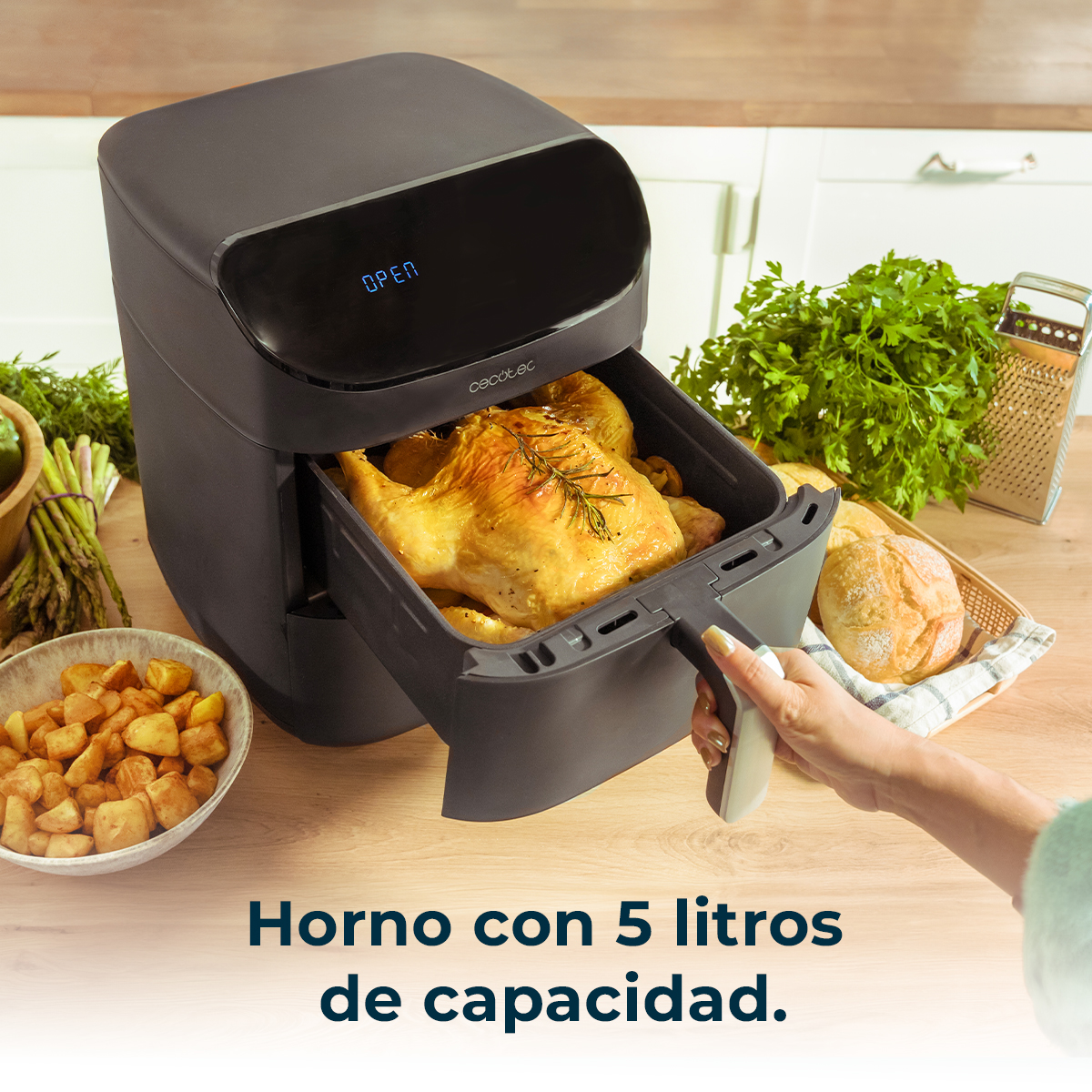 Frytownica powietrzna z pieczonym kurczakiem w środku. Na stole znajdują się inne potrawy.