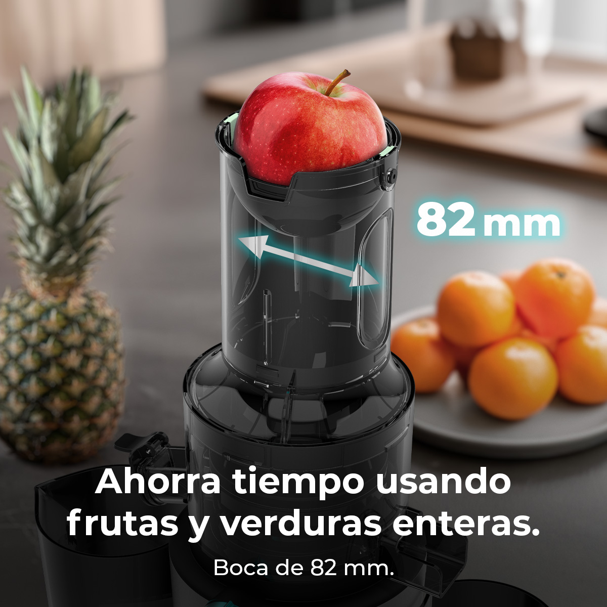 Una exprimidora con una manzana roja dentro. Piña y naranjas en el fondo, el texto dice 82 mm y Ahorra tiempo usando frutas y verduras enteras.