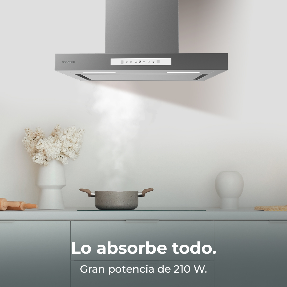 Scena in cucina con cappa sopra una pentola con vapore. Sono visibili anche fiori, un mattarello e un vaso.