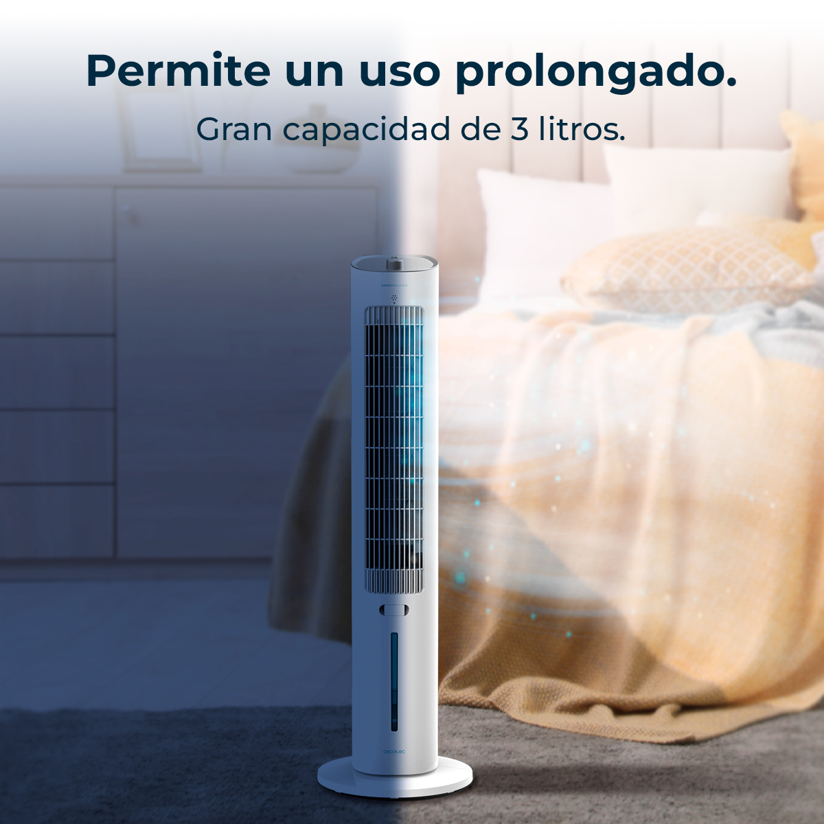 Un ventilatore a torre bianco si trova in una camera da letto. Il ventilatore è vicino a un letto con cuscini. Lo sfondo mostra un muro bianco e una finestra.