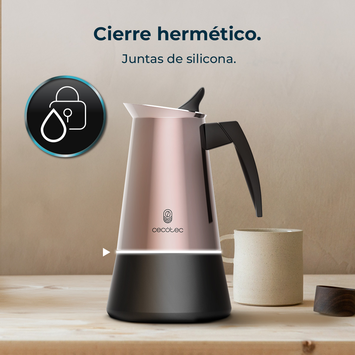 Una cafetera rosa dorada y negra con asa negra. Una taza blanca y un posavasos de madera sobre una superficie de madera.