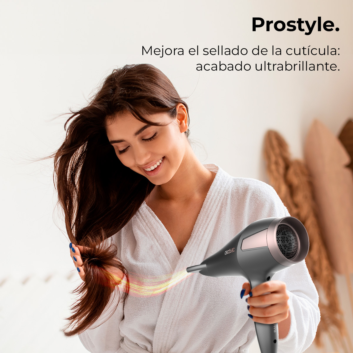 Una mujer sonríe, usando un secador de pelo. Lleva una bata blanca. Texto: 'Prostyle. Mejora el sellado de la cutícula: acabado ultrabrillante.'