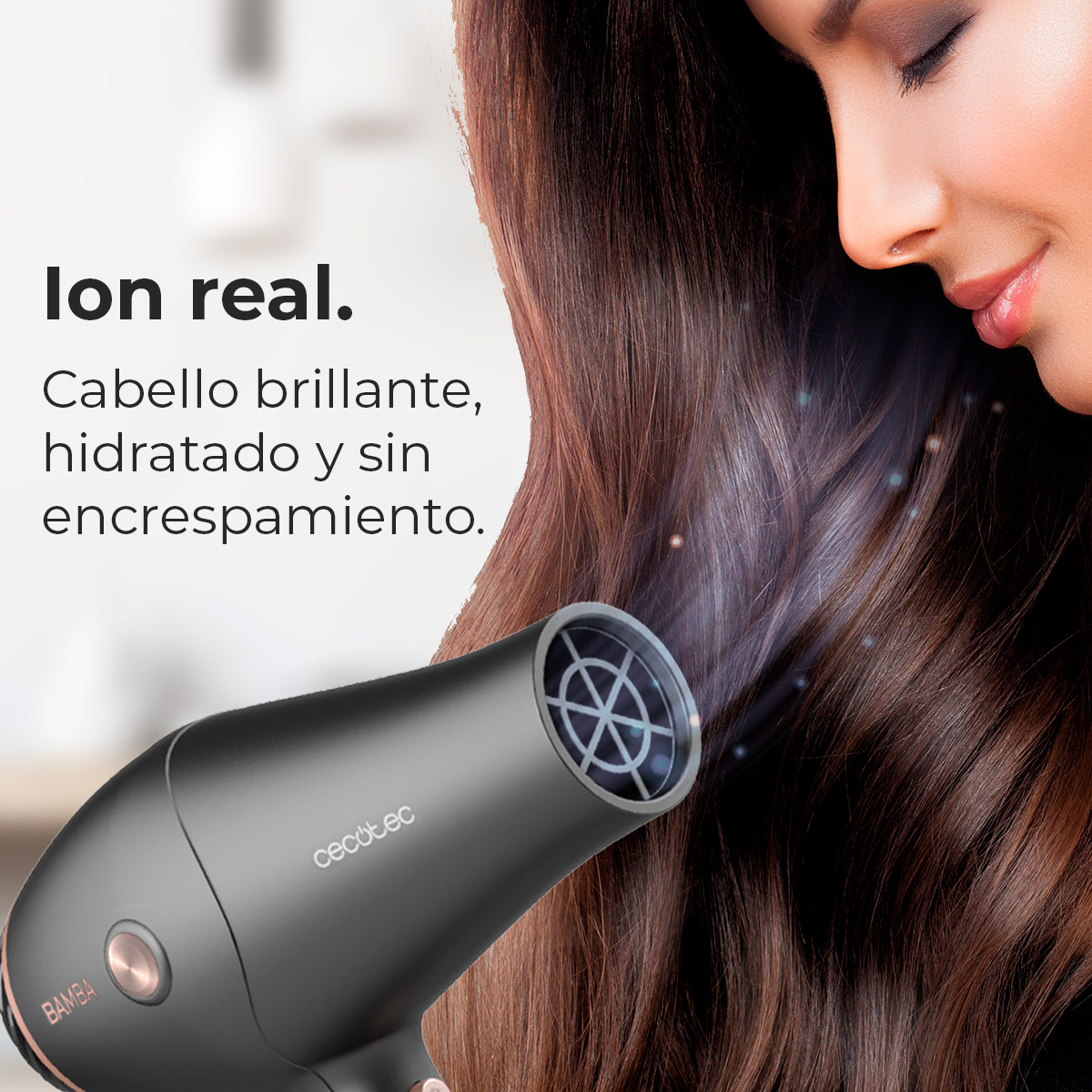 Una donna sorride. Un asciugacapelli nero soffia aria sui suoi capelli castano scuro. Testo: Ioni reali. Capelli lucenti, idratati.