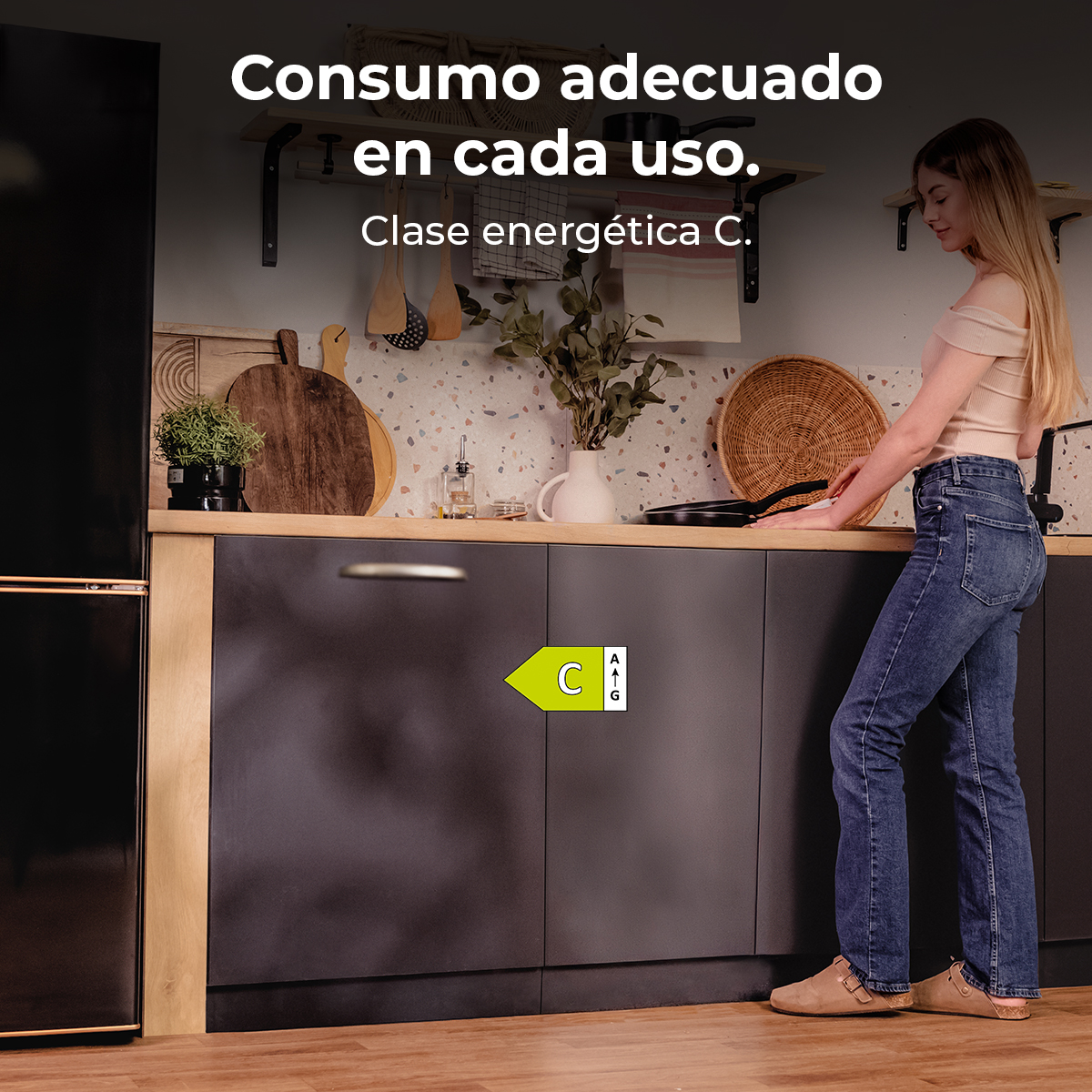Kobieta w kuchni ze zmywarką. Zmywarka ma etykietę energetyczną. Tekst na ścianie: 'Consumo adecuado en cada uso'.