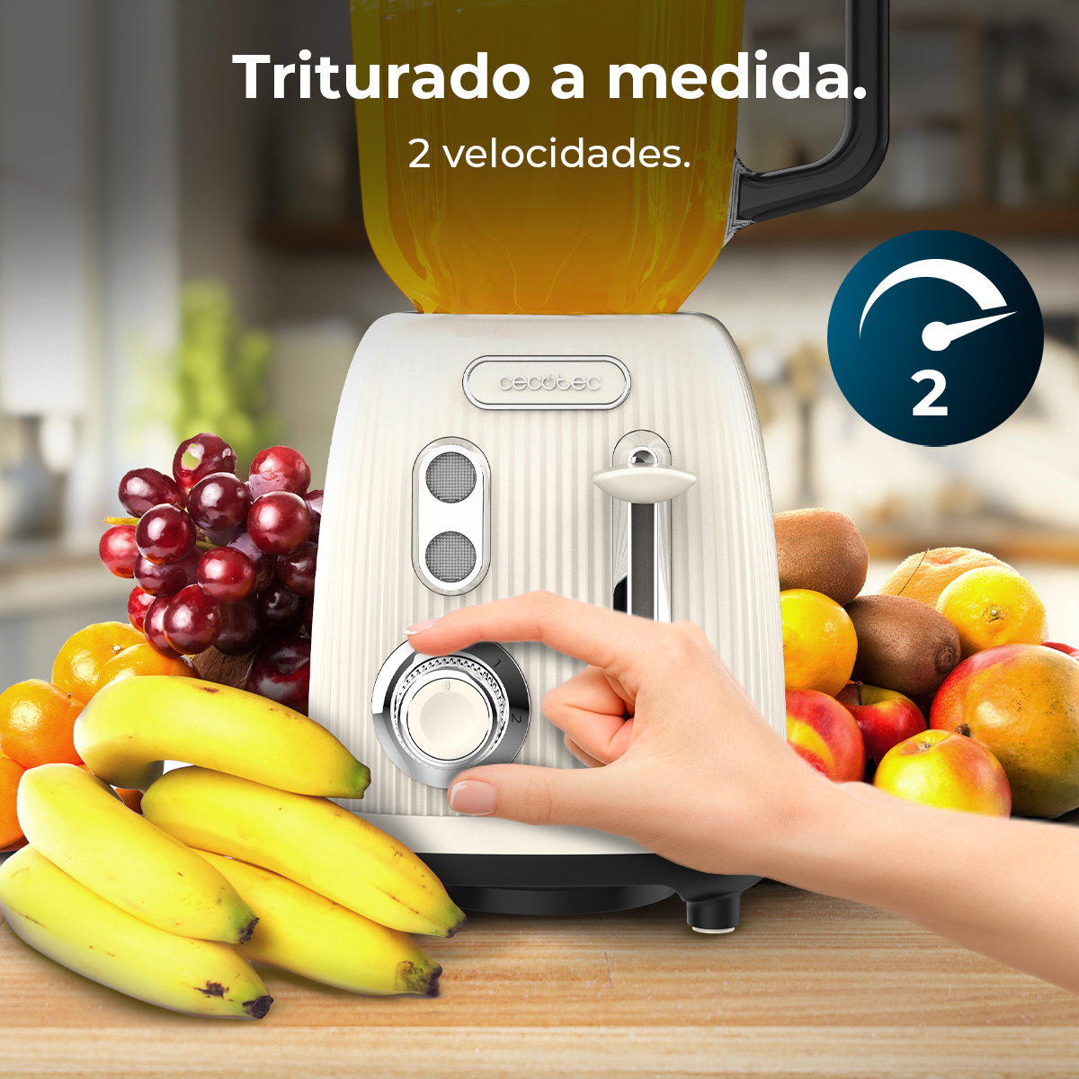 Un frullatore con frutta. Una mano gira la manopola della velocità. Banane, uva, mele, kiwi e arance in primo piano.