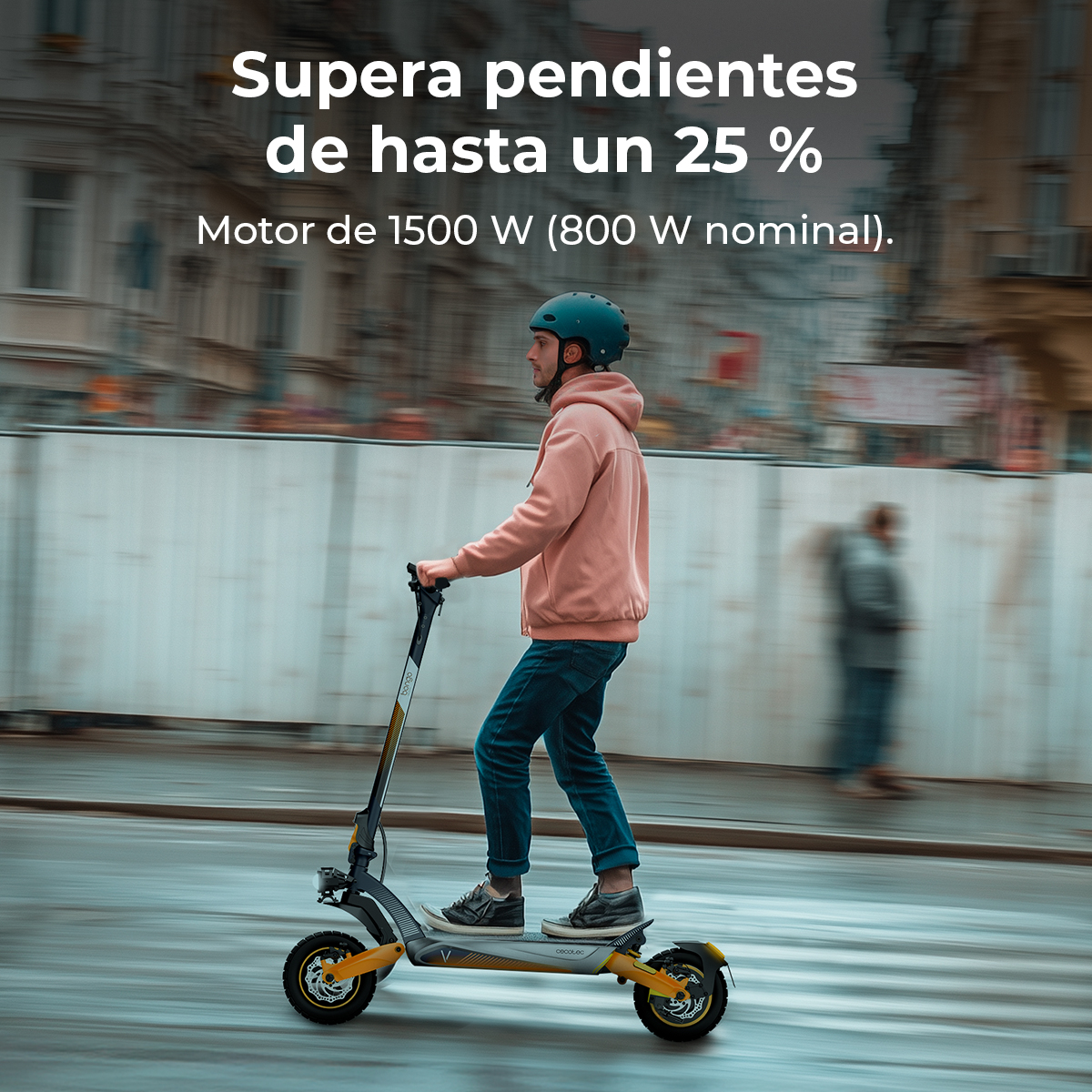 Un uomo guida un monopattino elettrico per le strade della città. Indossa un casco e una felpa con cappuccio. Lo sfondo sfocato mostra edifici e altre persone.