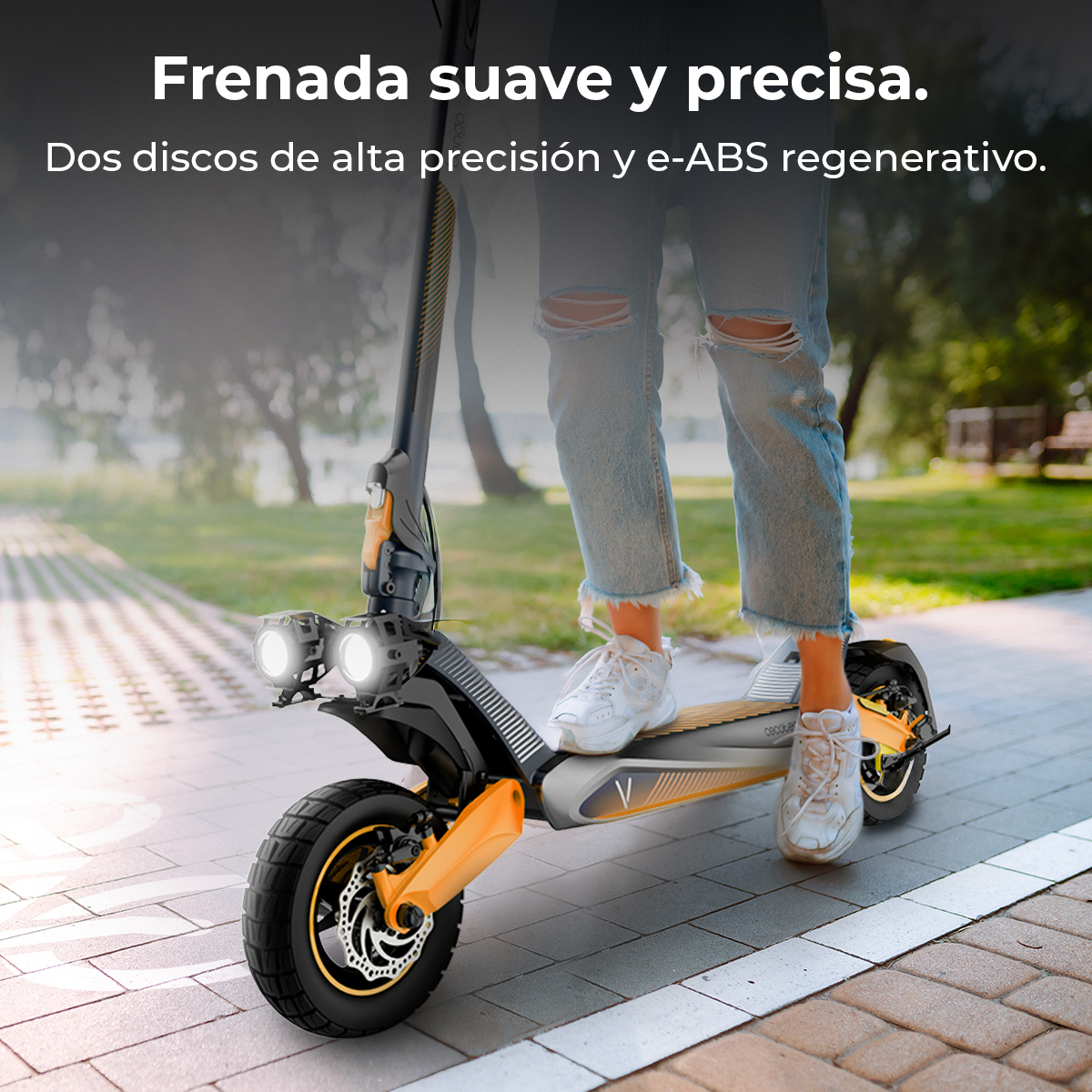 Una persona è in piedi su un monopattino elettrico con scarpe bianche. Lo scooter è nero e arancione su un sentiero pavimentato.