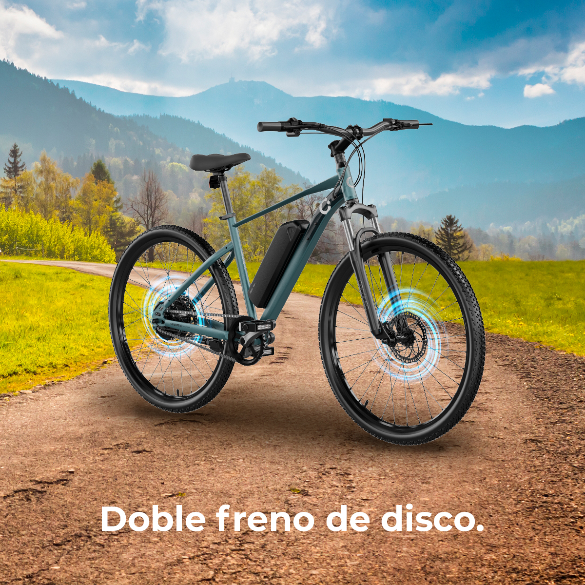 Una bicicletta elettrica con freni a disco è su uno sterrato. Lo sfondo presenta montagne e campi verdi sotto un cielo blu.