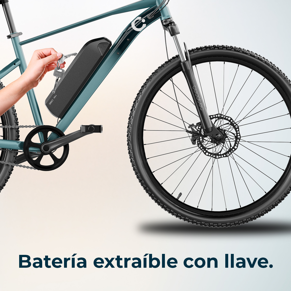 Una mano inserisce una chiave in una batteria nera su una bici verde acqua. La bici ha uno pneumatico nero e un freno a disco.