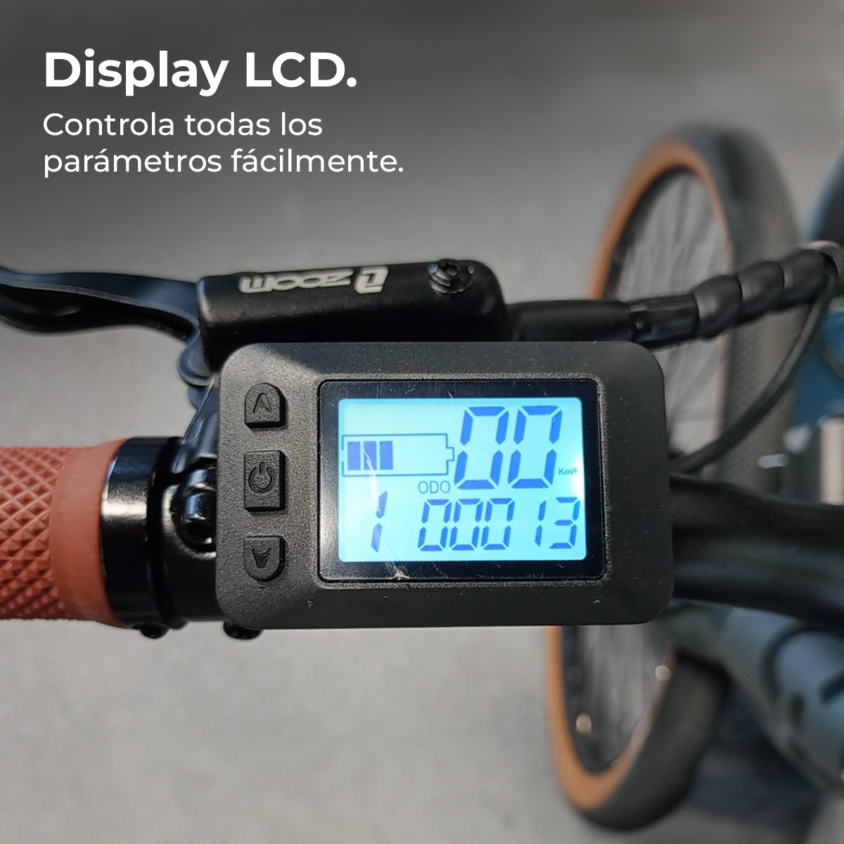 Primer plano de la pantalla LCD de una e-bike que muestra la velocidad, la batería y el odómetro. Se ven el manillar, los controles y parte de la rueda.