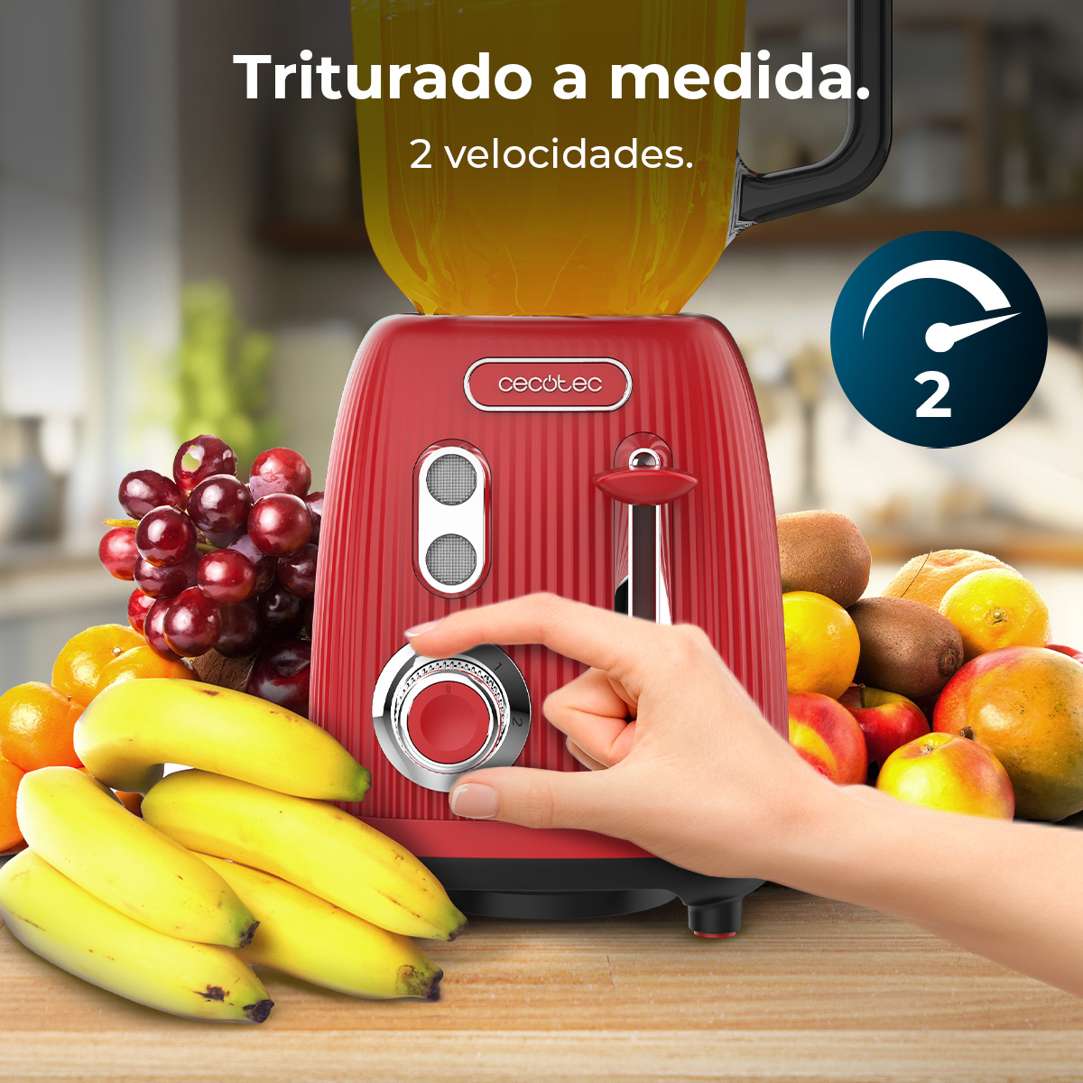 Un frullatore rosso con frutta. Una mano ruota la manopola della velocità. Testo: 'Triturado a medida. 2 velocidades.'