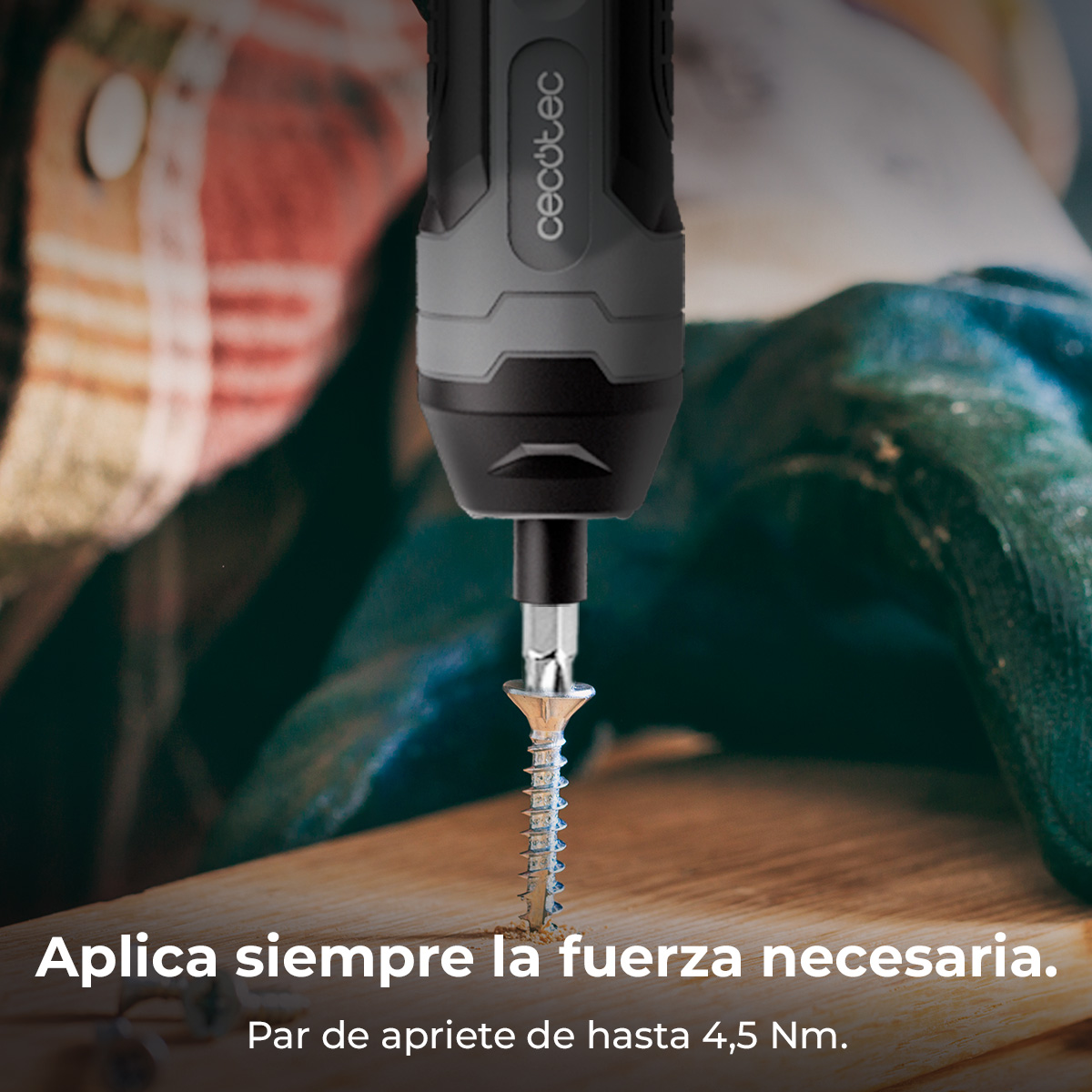 Un avvitatore elettrico che avvita una vite nel legno. L'avvitatore è nero e grigio, la vite è argentata e il legno marrone chiaro.