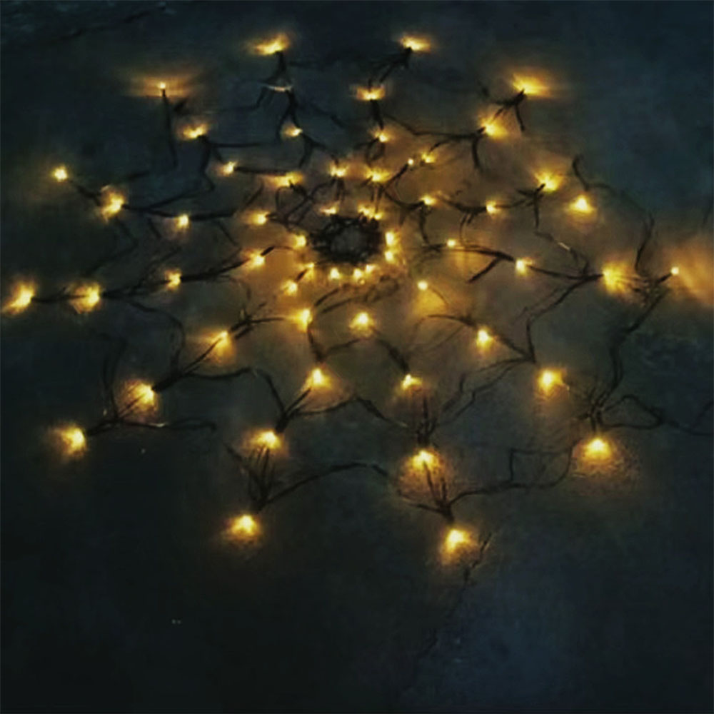 Eine sternförmige Anordnung warmer gelber Lichter auf einer dunklen Oberfläche. Die Lichter sind klein und gleichmäßig verteilt.